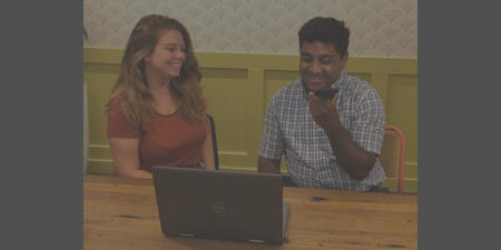 Photo of two people in front of a laptop